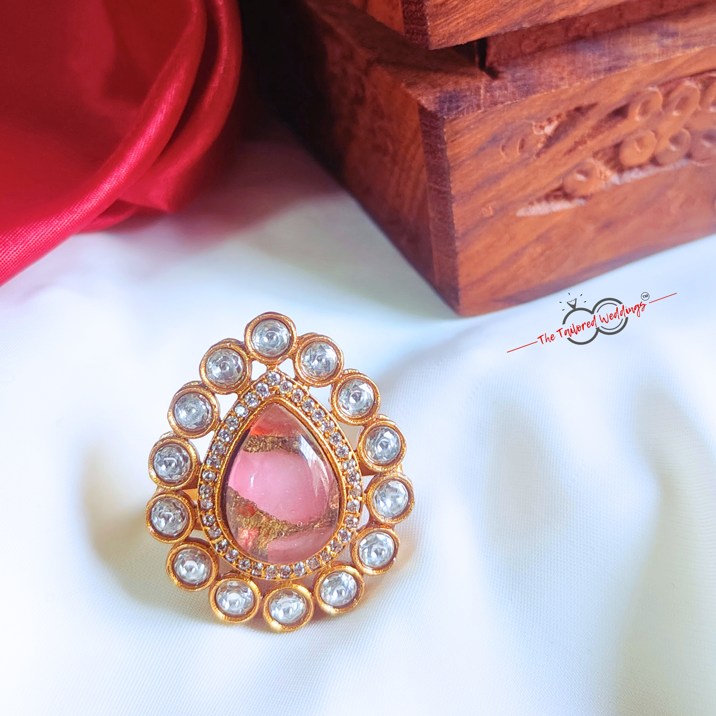 Decorative ring with pink center and gold and crystal accents on a white background