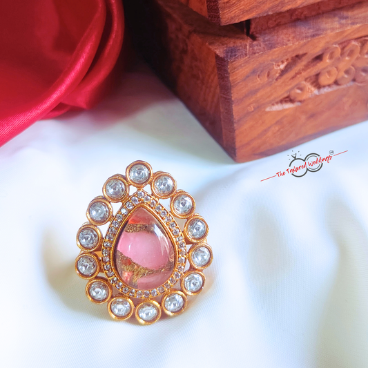 Decorative ring with pink center and gold and crystal accents on a white background