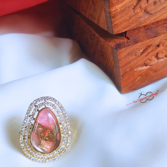 Pink gemstone ring with gold setting on a white fabric background